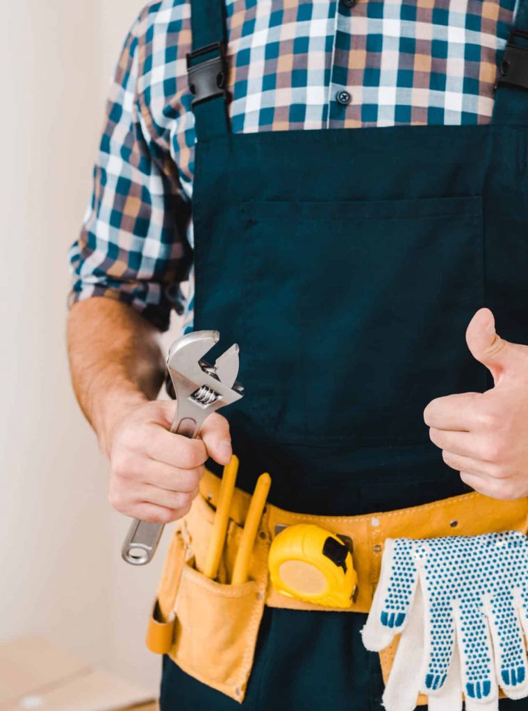 cropped view of handyman holding wrench and showing thumb up